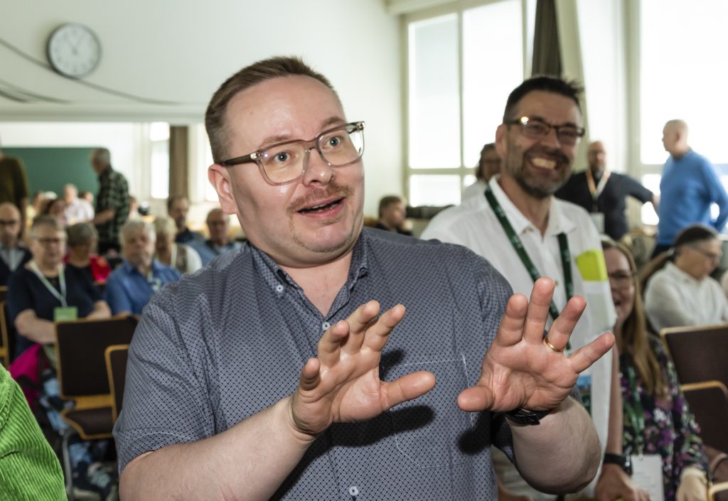 Mies puhuu ja kädet elehtivät.