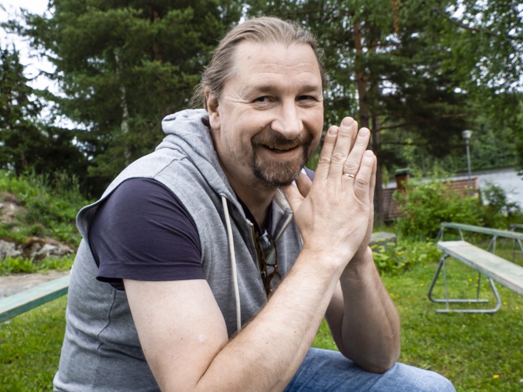 Mies istuu katsoen kameraan.
