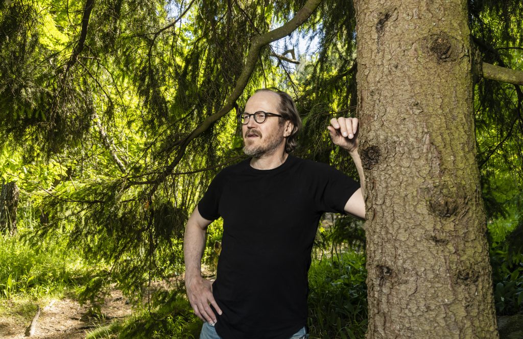 Mies nojaa puun runkoon.