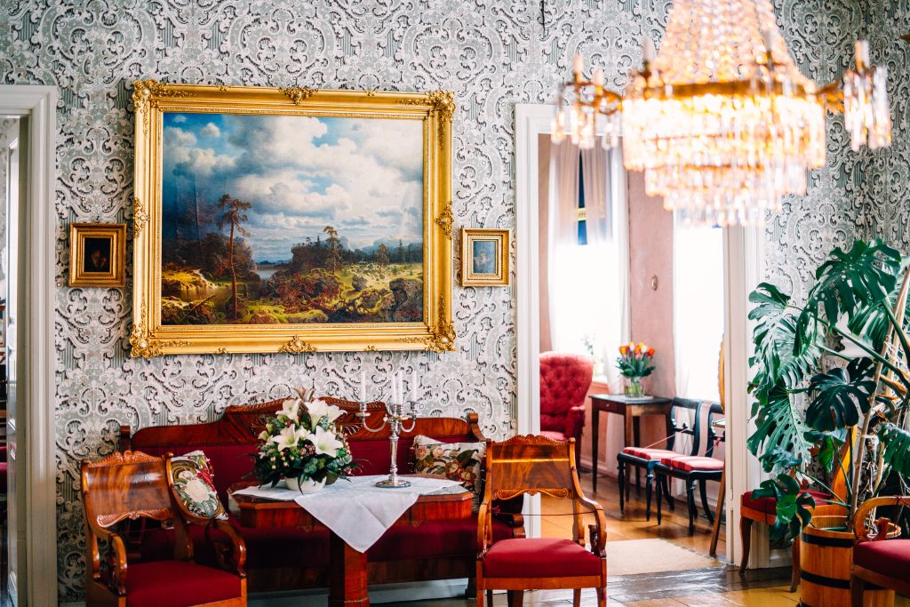 Kuvassa on museohuone sohvineen, pöytineen, tuoleineen tauluineen ja huonekasveineen