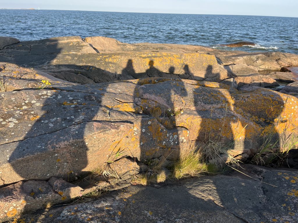 Kuvassa ihmisten varjokuvat heijastuvat rantakallioon