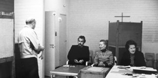 Mysteerikuva: Ketkä kaksi miestä ja naista huoneessa, jonka seinällä on risti?