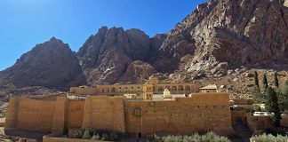 Ikivanha luostari palavan pensaan juurella lumoaa vaeltajan