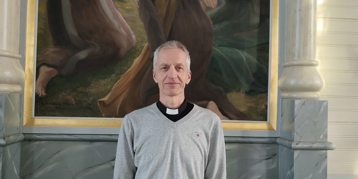 Erkki Lavanti by Henna Jylkkä mies seisoo alttaritaulun edessä ja katsoo suoraan kameraan