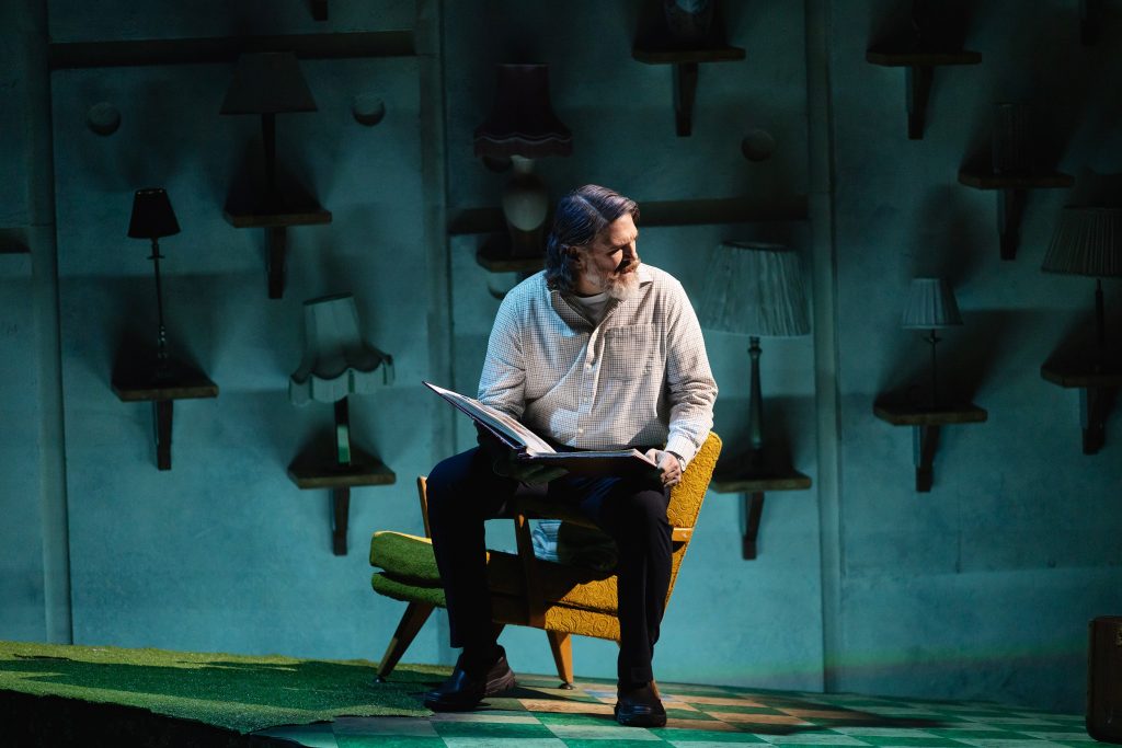 mies istuu näyttämöllä