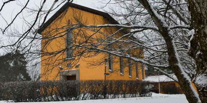 Tavlinen kuva keltaisesta rakennuksesta puutarhan keskellä.