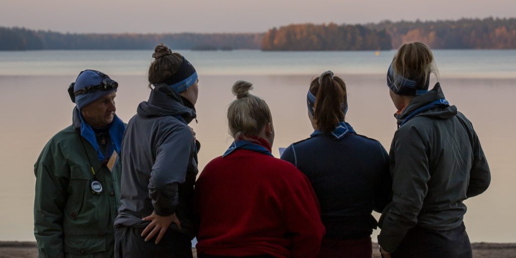 ihmisiä vesistön äärellä katsomassa pois päin kamerasta