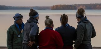 ihmisiä vesistön äärellä katsomassa pois päin kamerasta