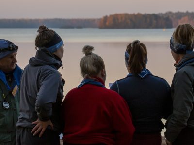ihmisiä vesistön äärellä katsomassa pois päin kamerasta
