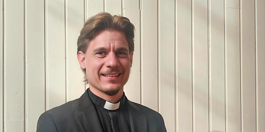 miespappi seisoo seinustalla ja katsoo kameraan