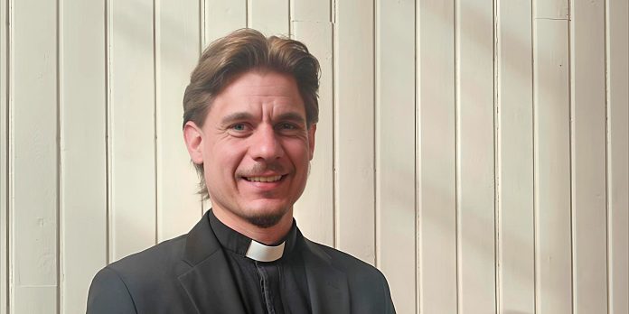 miespappi seisoo seinustalla ja katsoo kameraan