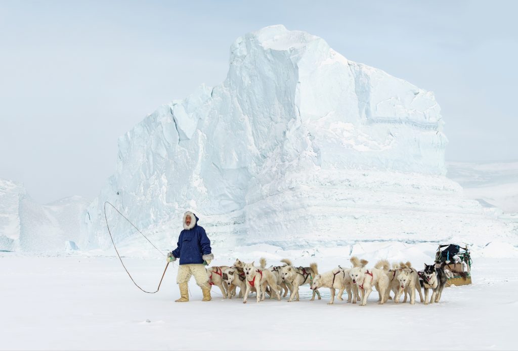 mies ja koiravaljakko jäävuoren edessä