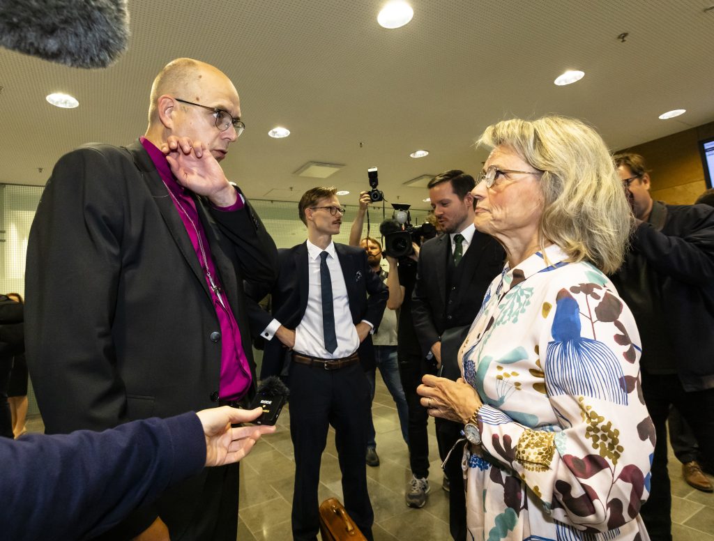 Oikeudessa syytettynä olevat Juhana Pohjola ja Päivi Räsänen seisovat vastakkain keskustelemassa vakavan oloisina.