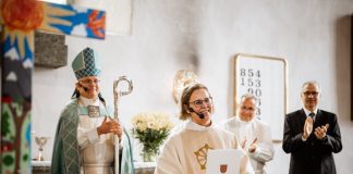Porvoon hiippakunnan tuomiorovastiksi valittu Camilla Ekholm: ”Jo oli aikakin rikkoa lasikatto” Papiksi pukeutunut henkilö seisoo kirkon etuosassa ja pitelee asiakirjaa. Taustalla alttarilla seisoo piispan asuun pukeutunut henkilö sauvoineen sekä kaksi muuta henkilöä, jotka taputtavat. Kirkon sisätila on valoisa, ja etualalla näkyy osittain värikäs koriste.