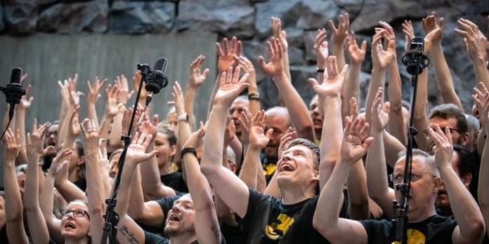 kuoro laulaa kädet ojossa kohti taivasta