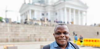 LML:n Afrikan aluesihteeri: Kenian kirkon eronsa syyksi ilmoittamat väitteet LML:sta ovat vastuuttomia Afrikkalainen mies seisoo hymyillen Helsingin Senaatintorilla taustanaan tuomiokirkko.