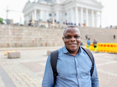 Afrikkalainen mies seisoo hymyillen Helsingin Senaatintorilla taustanaan tuomiokirkko.