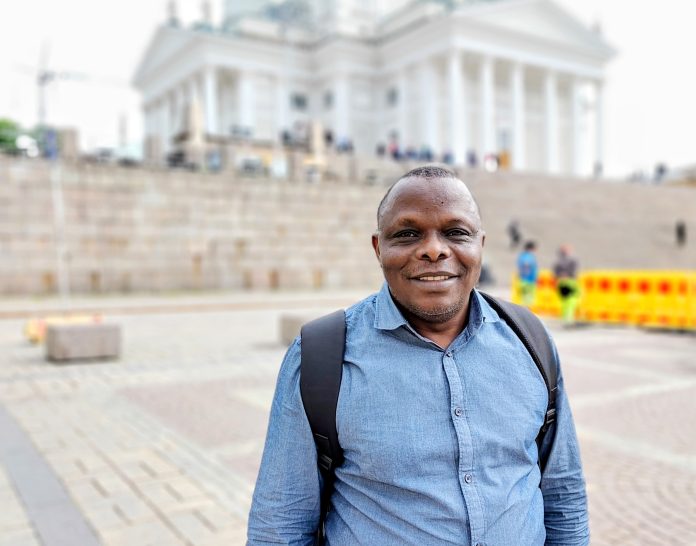 Afrikkalainen mies seisoo hymyillen Helsingin Senaatintorilla taustanaan tuomiokirkko.
