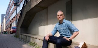 mies istuu kivetyksellä ja katsoo kameraan