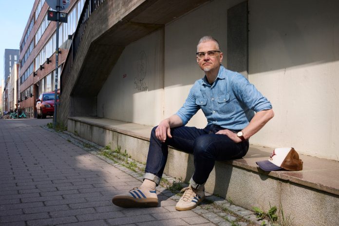 mies istuu kivetyksellä ja katsoo kameraan