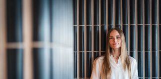 Eeva Toivonen huolehtii, että kirkon työntekijöiden eläkevarallisuus on sijoitettu paitsi tuottavasti myös vastuullisesti Vaaleaan puseroon pukeutunut pitkähiuksinen henkilö seisoo sisätilassa tumman pystylaatoitetun seinän edessä ja katsoo kameraan.