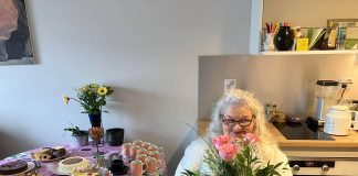 70-vuotias konfirmoitu Eija Seppänen istuu alba yllään pyörätuolissa kotonaan.