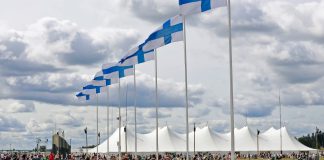 rivi suomen lippuja ja taustalla seurateltta