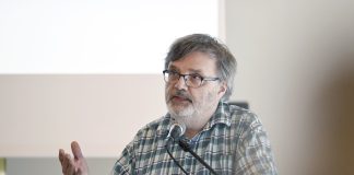 Parrakas silmälasipäinen professori Antti Laato puhuu teologisen symposiumin puhujakorokkeella.