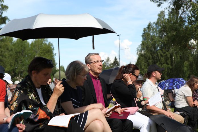IMG_1253 Jukka Keskitalo Ylivieskan herättäjäjuhlilla by Freija Özcan Piispa Keskitalo istuu Ylivieskan herättäjäjuhlilla taivasalla seurapenkissä.
