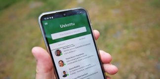 kännykkä kädessä ja kännykässä näkyy uskottu-sovellus