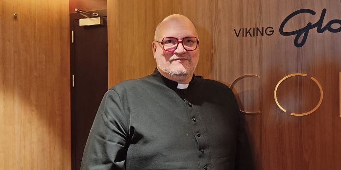 Jokiläänin kirkkoherra Teemu Salminen puolilähikuvba miespapista, joka nojaa seinään ja katsoo kameraan