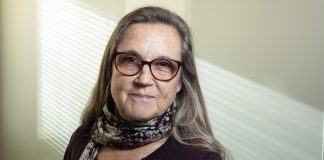 Kolumni: En osaa kieltä enkä pääse ehtoolliselle, mutta papin ojentama ruusu ottaa osaksi yhteisöä Kuvassa puolilähikuva silmälasipäisestä, pitkähiuksisesta naisesta. Taustalla vaalealle seinälle siiloutuu arugingon valoa ikkunasta.