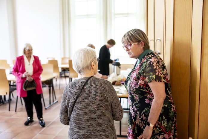 Diakoni Tarja Vesikallio Kuvassa iäkkäitä naisia salissa.