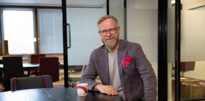 artikkeli-paakuva-30 kopio Silmälasipäinen mies istuu ja nojaa pöytään rintataskussaan Levis-huivi.