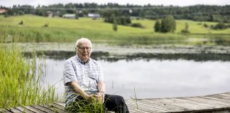 Vanha mies istuu laiturilla veden äärellä.