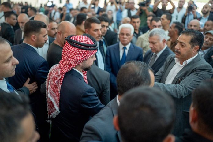 Palestiinalaishuiviin pukeutunut prinssi seisoo väkijoukossa ja kättelee ihmisiä.