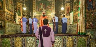 Armenialaisia pappeja Vankin katedraalin alttarilla selin kameraan Isfahanissa Iranissa.