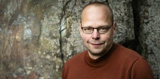 Pyhän Henrikin säätiön kulttuuripalkinto Roope Lipastille Kirjailija Roope Lipasti yllään viininpunainen pitkähihainen paita.